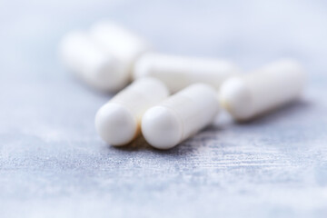 Creatine capsules on bright wooden background. Soft focus. Close up. Copy space.	