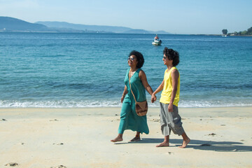 couple in love walking hand in hand along the beach shore