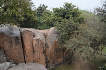 Obraz premium An image of the Huge boulders looking like a small hill to climb in one of the trails of a trek during the monsoon in the Aravalli Hills of Delhi in India.