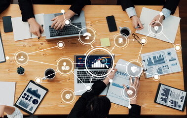 A diverse group of professionals engaging in a management meeting with laptops and documents, utilizing visual data and technology to drive strategic discussions and decision-making. Amity