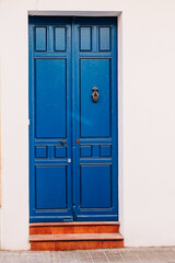 A vibrant blue door stands out against a white wall, evoking the traditional Mediterranean style.
