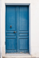 A classic blue door contrasting against a white wall, evoking a timeless Mediterranean style.