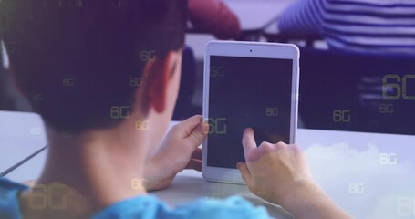 Boy tapping tablet in classroom, displaying floating 6G icons and education technology concept - Powered by Adobe
