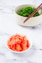 Chuka salad, made from fresh seaweed, with sesame dressing, in a white bowl, with chopsticks and pickled ginger, without people,