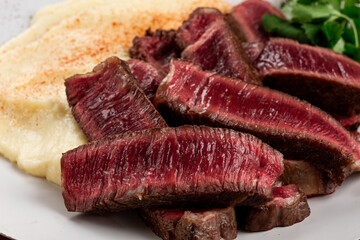 Sliced steak, served with creamy mashed potatoes, and fresh herbs, no people