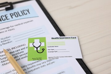 Medical insurance card, policy and pen on white wooden table, closeup