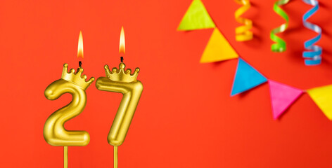 Number 27 candle - Birthday celebration on an orange background with pennants