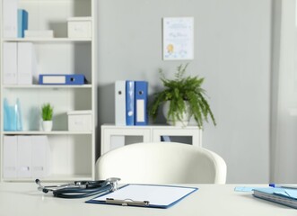 Doctor's workplace. Stethoscope, clipboard and other stationery on white table in medical office