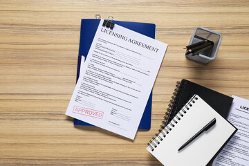 Licensing agreement document and stationery on wooden table, flat lay