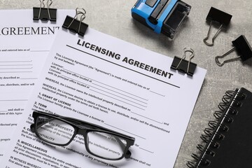 Licensing agreement documents, stationery and stamp on gray textured table, flat lay