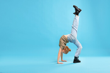 Girl in stylish clothes dancing on light blue background, space for text