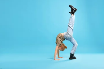 Girl in stylish clothes dancing on light blue background, space for text