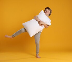 Cute boy with pillow on orange background