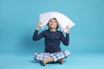 Cute boy with pillow on light blue background © New Africa