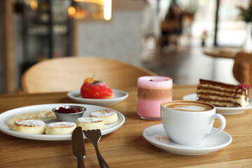 Delicious cottage cheese pancakes, desserts and aromatic coffee served on wooden table in cafe