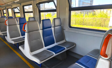 Empty carriage of intercity electric train, trains with blue and gray seats near the window. City transport, interior of the carriage. Travel by train