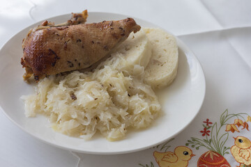Roasted duck leg with yeast dumpling and cabbage on a white plate. Tasty lunch