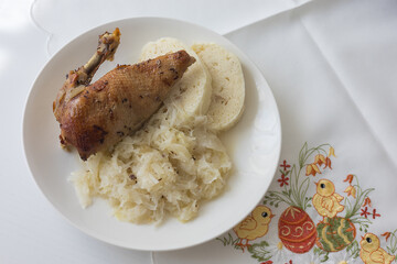 Roasted duck leg with yeast dumpling and cabbage on a white plate. Tasty lunch
