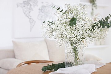 Bouquet of beautiful gypsophila flowers and eucalyptus branches in vase on table indoors. Space for text