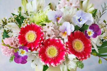 Beautiful bouquet of spring flowers in a vase closeup , gerberas, alstroemeria, pansies, hyacinths. Card for spring holidays