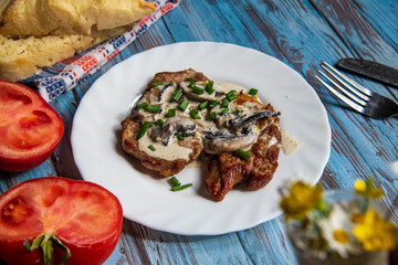 Pan seared pork steak on a wooden table with white sauce,pork fillet with dressing..