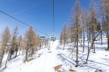 Winter ski lift in snowy mountain landscape with clear blue sky