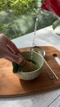 Crafting authentic matcha tea: pouring, whisking, and blending in sunlit serenity