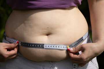 Woman's belly with fat. A plump woman measures her belly.