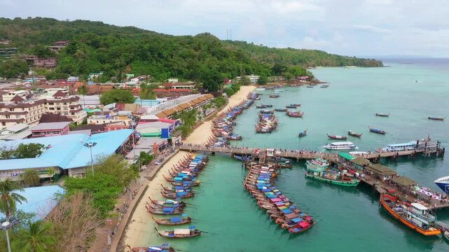 Pier buzzes as ferry passengers land on Koh Phi Phi, Thailand. Aerial drone video