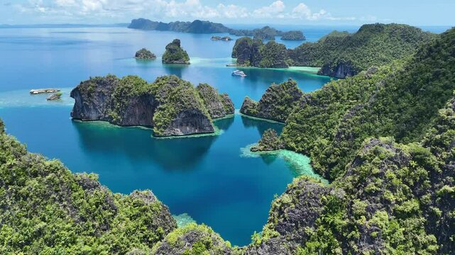 Rugged limestone islands rise from the seascape in Misool, Raja Ampat, Indonesia. This area is known as the heart of marine biodiversity and is a popular destination for diving and snorkeling.