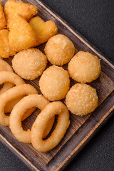 Food, chicken nuggets, onion rings and cheese balls on dark background