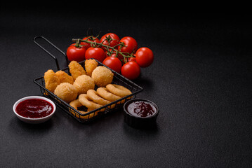 Food, chicken nuggets, onion rings and cheese balls on dark background