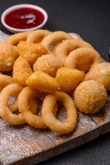 Food, chicken nuggets, onion rings and cheese balls on dark background