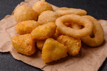 Food, chicken nuggets, onion rings and cheese balls on dark background