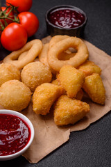 Food, chicken nuggets, onion rings and cheese balls on dark background