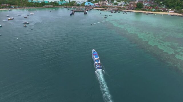 Tour ferry glides into harbor on Koh Phi Phi, Thailand. Aerial drone video