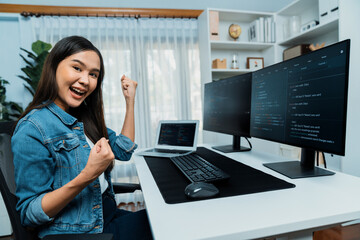 Young Asian IT developer creating raising fist up with successful information on pc with coding...