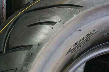 Close-up of the side of a new road motorcycle rear tire with the direction of rotation indicated