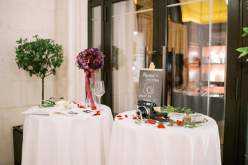Fujifilm Instax camera lies on the table among the flower petals near the sign. Caption: Memory Station