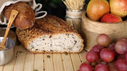 Artisan bread with seeds, fresh grapes, wooden bowl of pears, wheat bundle, burlap sack on wooden surface, showcasing organic, farm-to-table theme perfect for cozy, healthy lifestyle visuals.