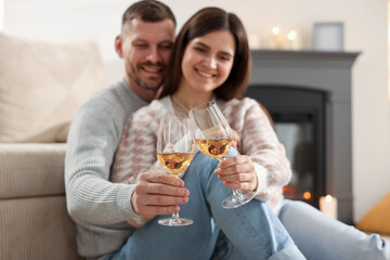 Happy couple clinking glasses of wine indoors, selective focus