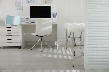 Doctor's workplace with modern computer and examination table in medical office