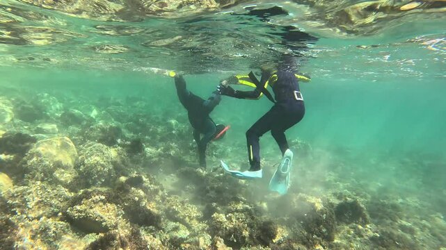 Father and son in wetsuits fishing for octopus in the Mediterranean