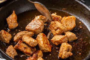 Chicken pieces are fried in a frying pan in sauce and spices