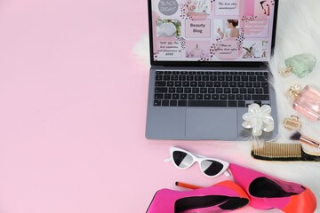 Laptop with beauty blog web site, shoes, perfumes and different accessories on pink background,...