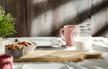 Cozy morning breakfast with waffles, croissant and milk and hot coffee on rustic wooden table. Warm sun light on wall background.