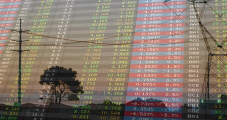Stock market data overlay showing dusk landscape, with tower silhouette and colored numbers - Powered by Adobe