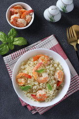 Italian ditalini pasta with shrimps and basil in white bowl on dark background, Top view