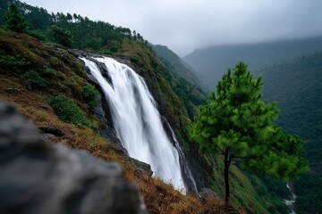 Fototapeta premium Majestic waterfall cascades through mountain terrain in misty weather
