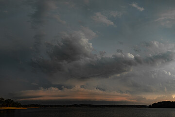 Dark storm clouds gathering over the lake during a dramatic sunset